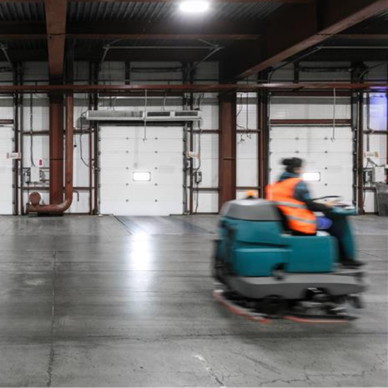 Worker driving floor scrubber